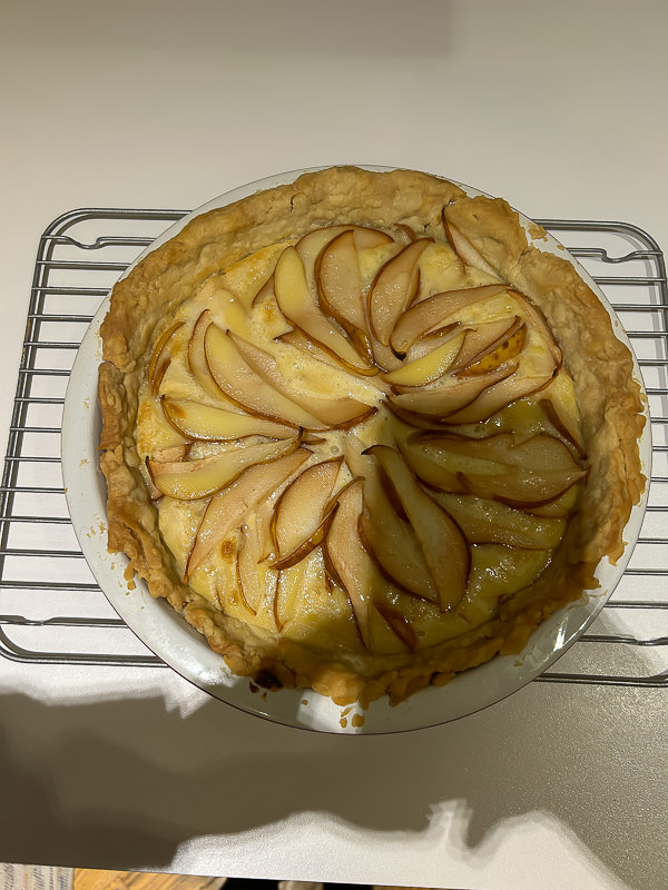 An iPhone photo of a pear pie taken in very bad lighting in a kitchen at home under overhead lights.